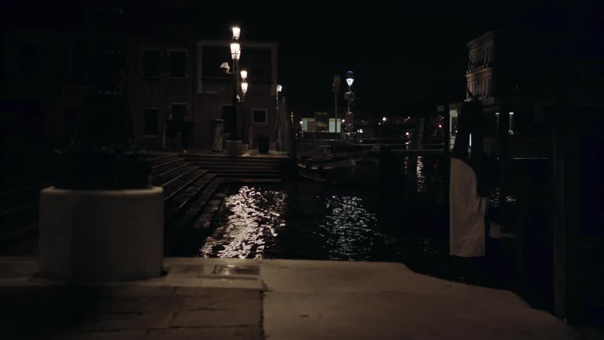 The water splashes against the pier at night