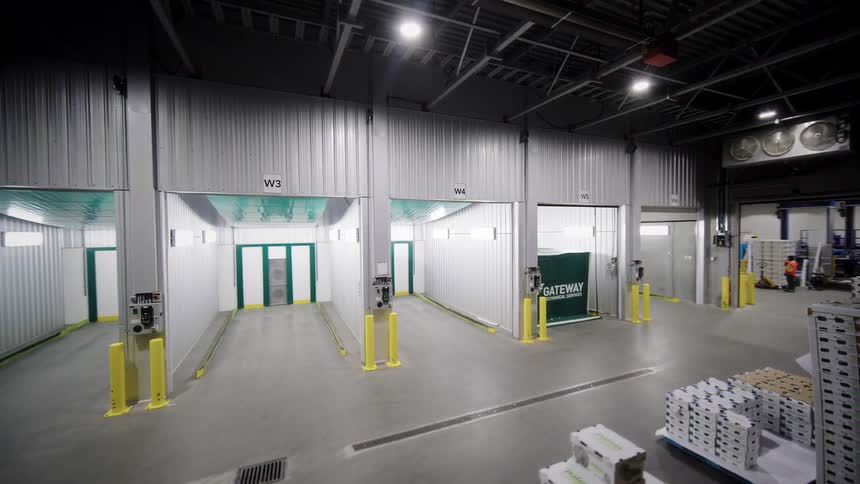 A slow pan shot reveals the interior of a large, modern logistics warehouse with multiple loading bay doors