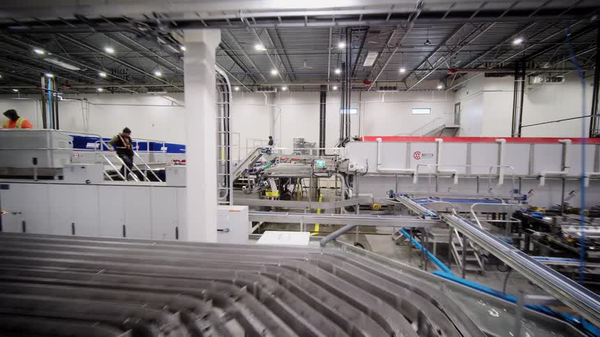 A cinematic pull-back reveal of a large-scale, automated food processing and packaging warehouse with complex conveyor systems
