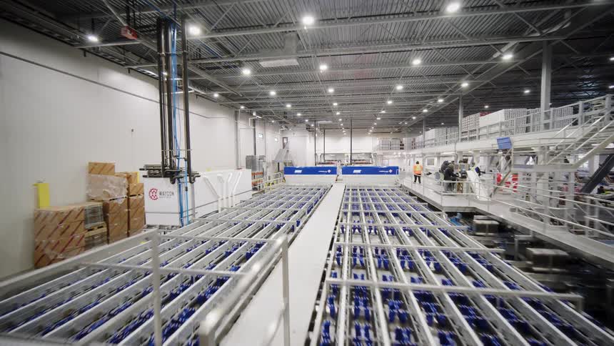 A wide-angle tracking shot over a state-of-the-art automated conveyor system in a large, modern logistics warehouse