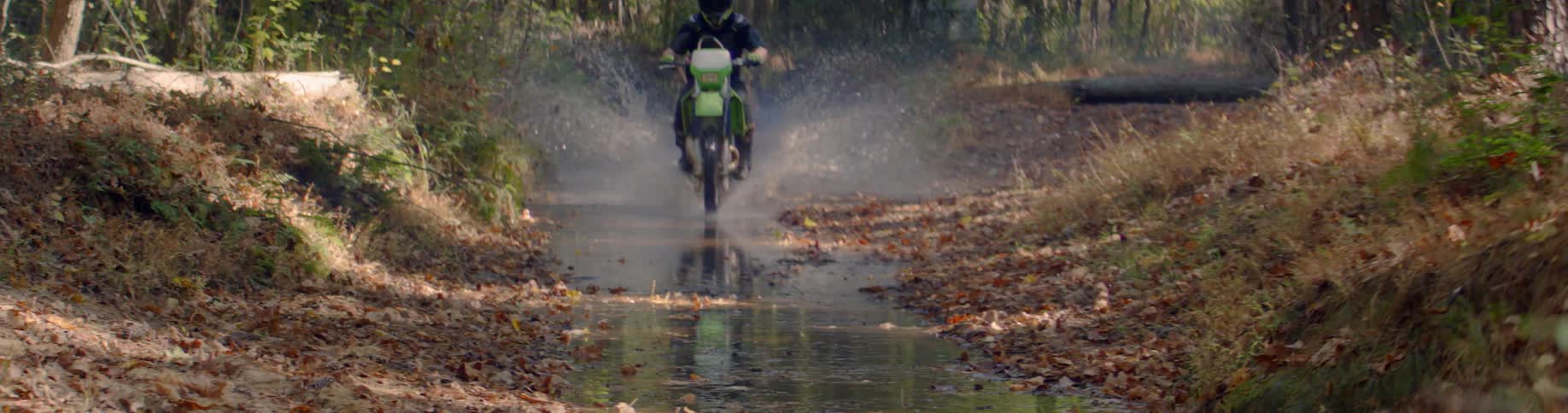 Person rides a motorcycle through a creek