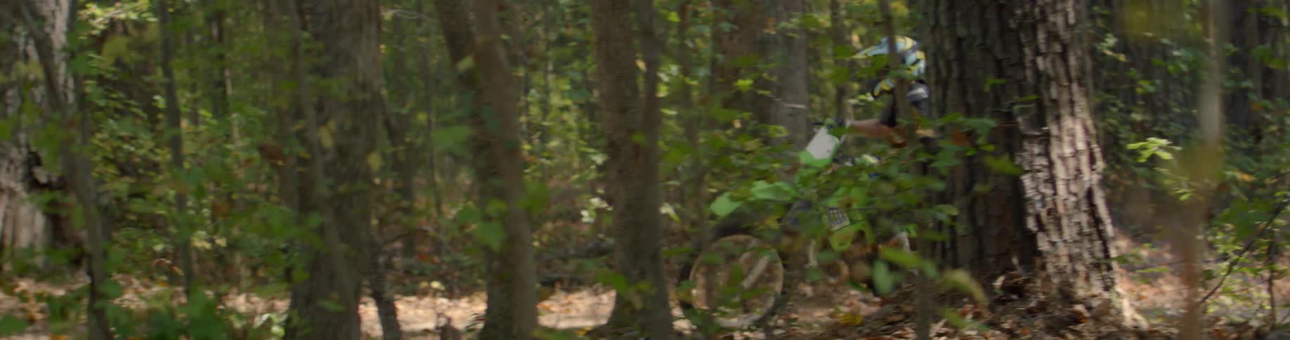 A dirt bike rider travels uphill in the forest