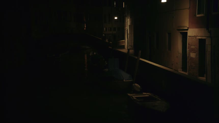 People walk through a dimly lit city alley at night