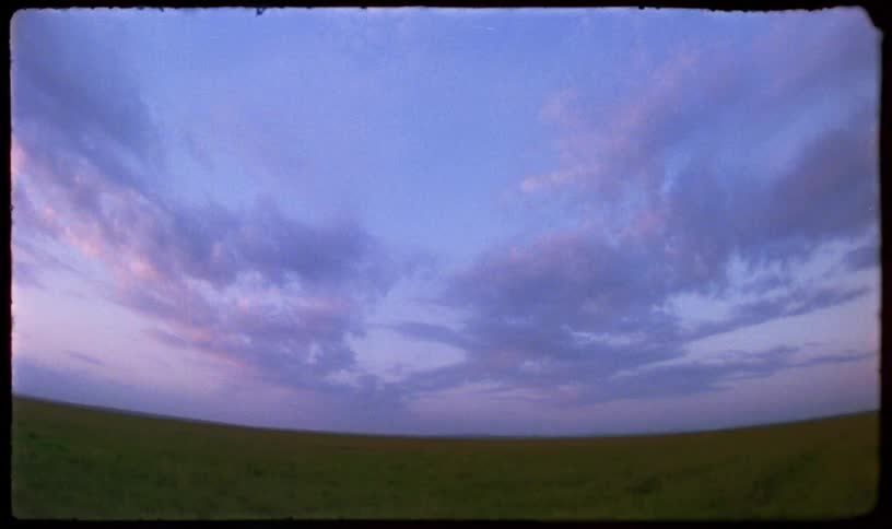 A serene, wide-angle view of a vast green prairie under a beautiful purple and pink twilight sky on vintage film