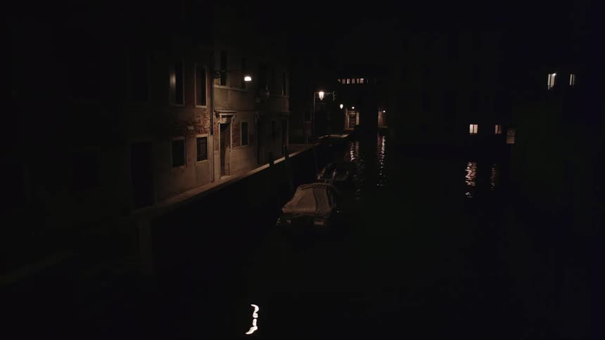Water ripples and flows next to a building at night