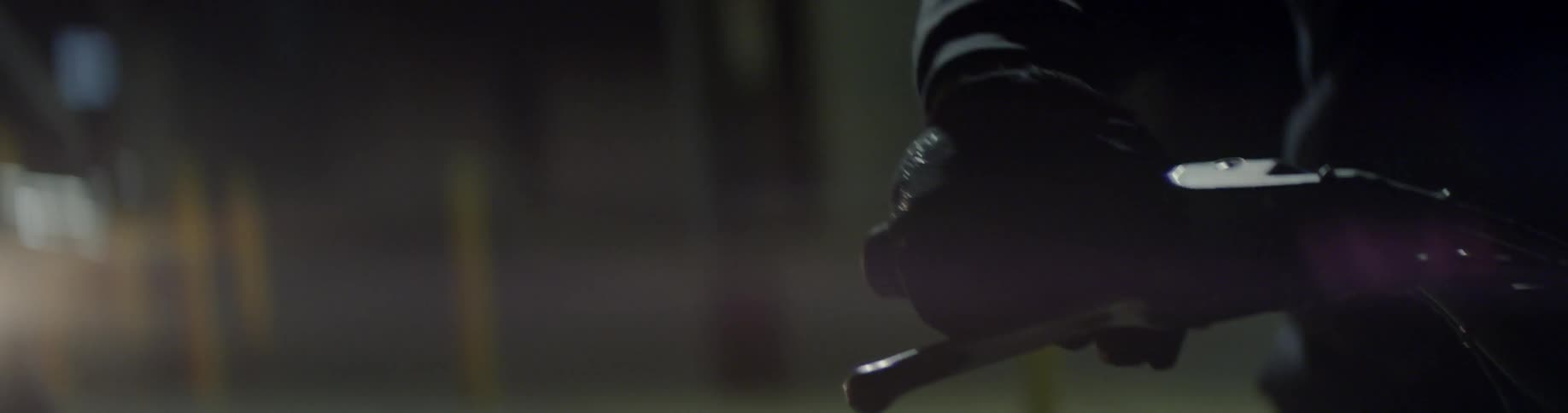 A gloved hand revs a motorcycle engine at night
