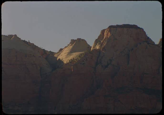 A vintage shot captures the sunlight illuminating the peaks of a majestic desert mountain range