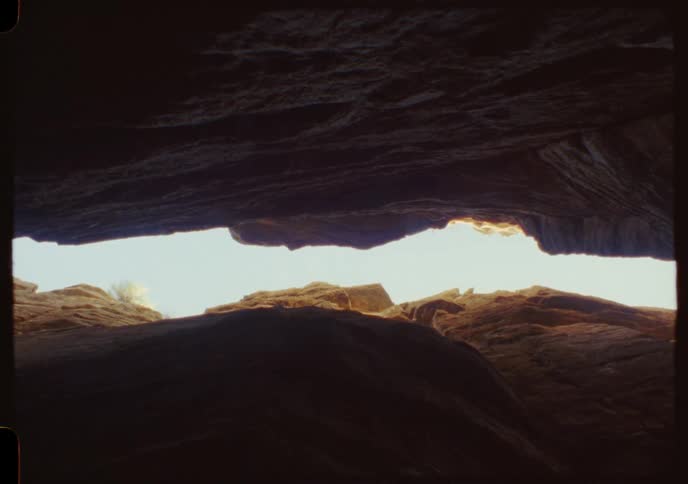 A handmade puppet dangles in the light from the shadows of a desert cave in this vintage-style shot