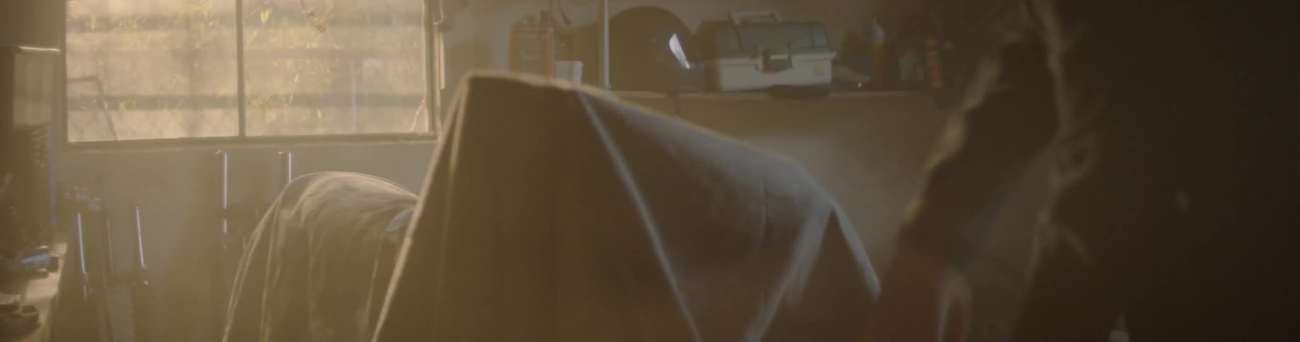 Person uncovers a motorcycle in a garage