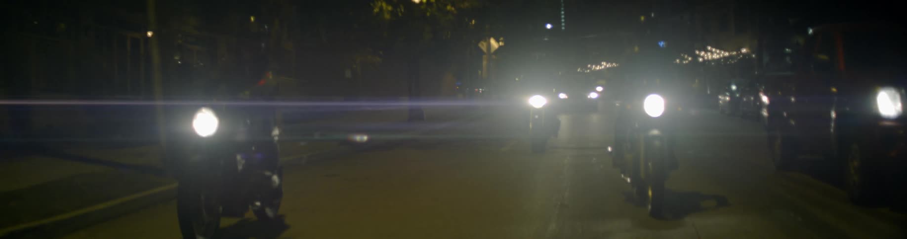 Motorcycles driving down a city street at night