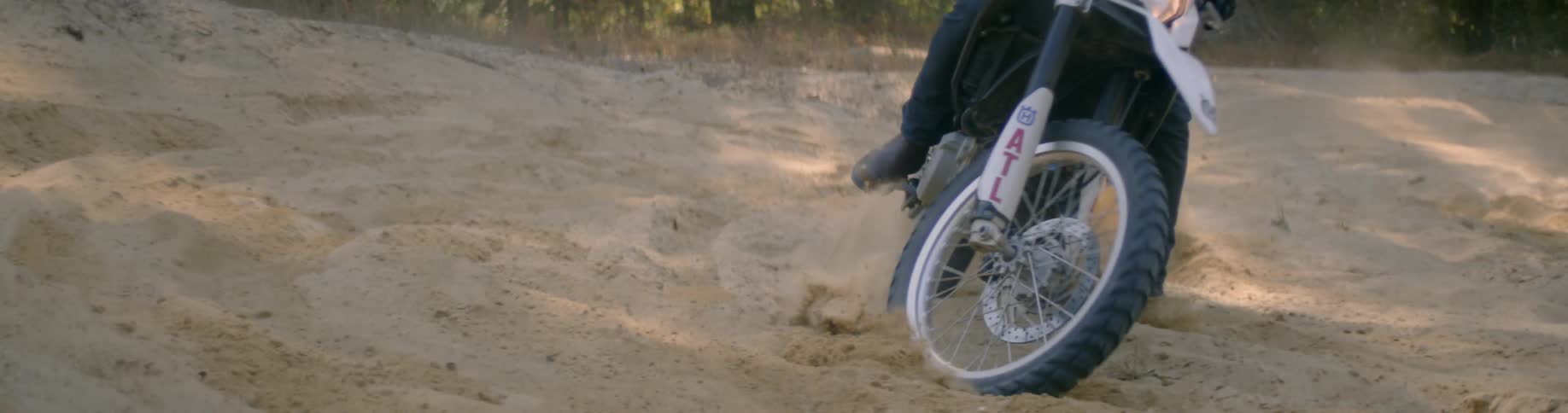 A person turns on a dirt bike throwing dirt everywhere
