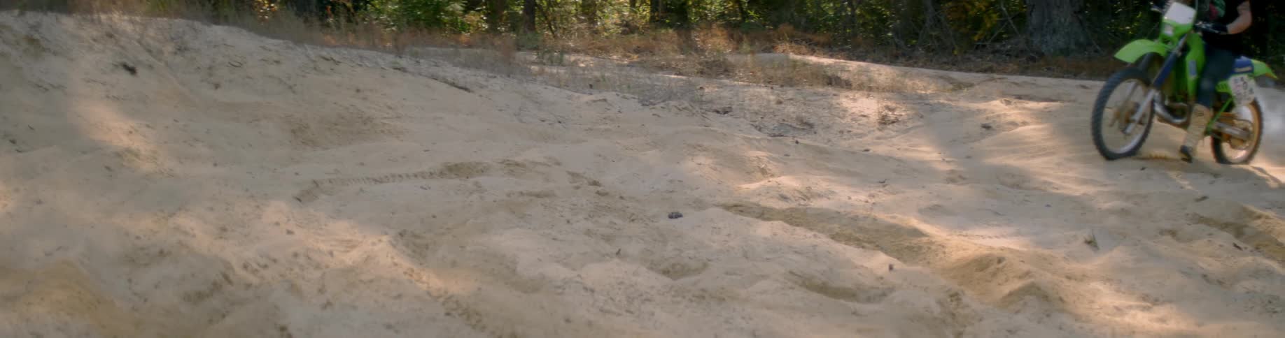 A dirt bike rides through a sandy area
