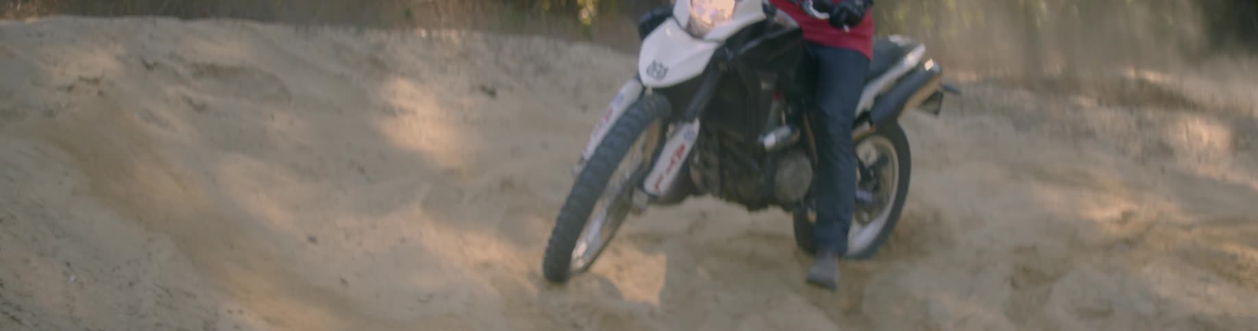 A man rides a dirt bike while kicking up dust