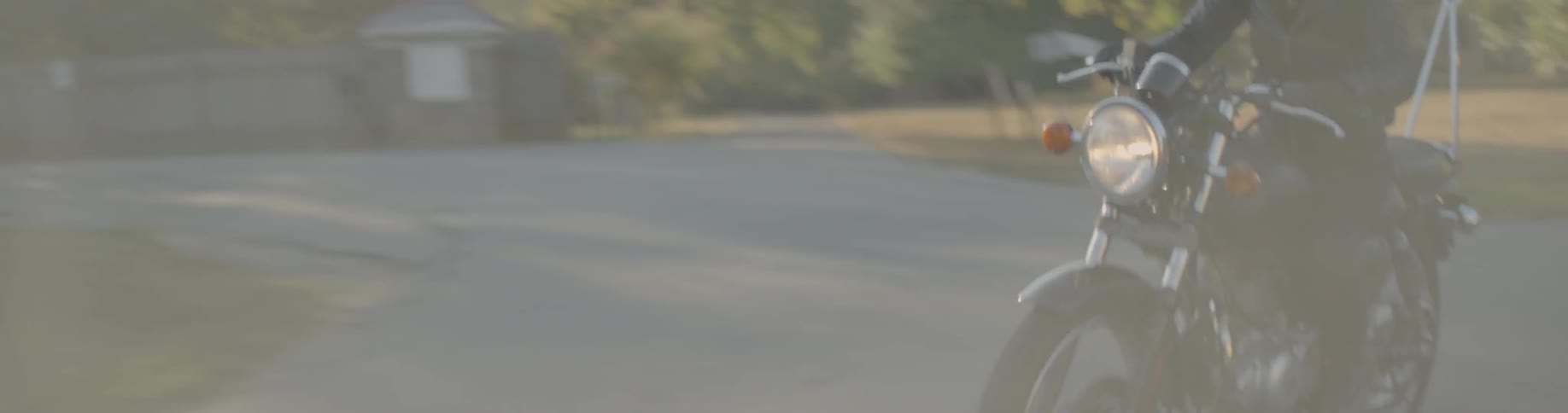 Motorcycle driving down a country road near houses