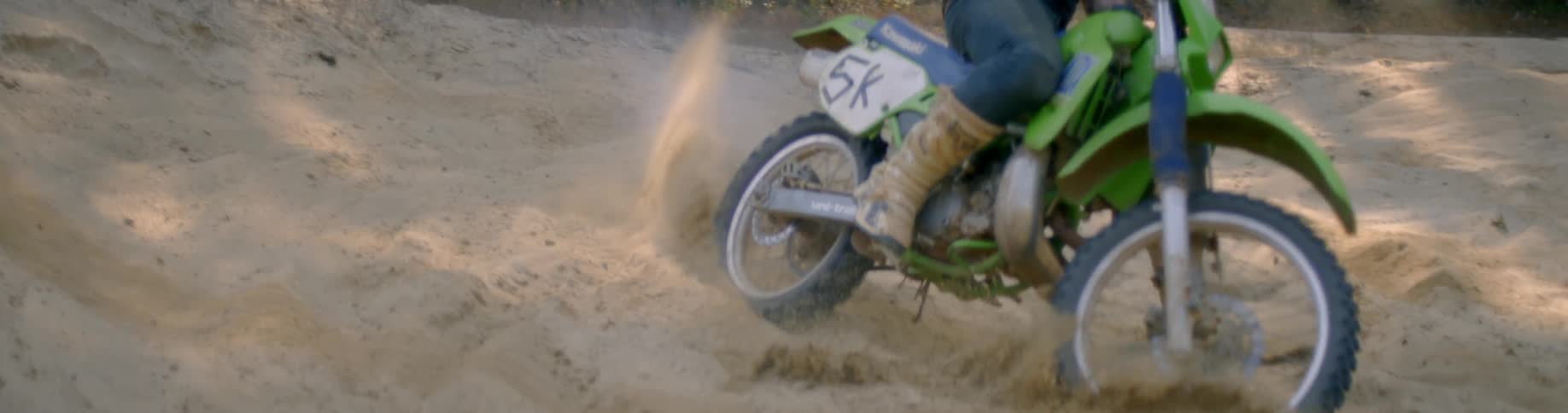 A person rides a dirt bike through the sand