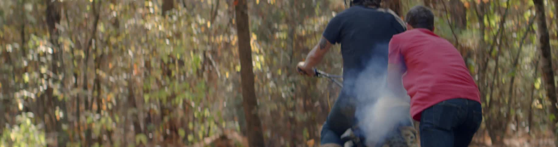 A motorcycle spews smoke as it's ridden in a forest