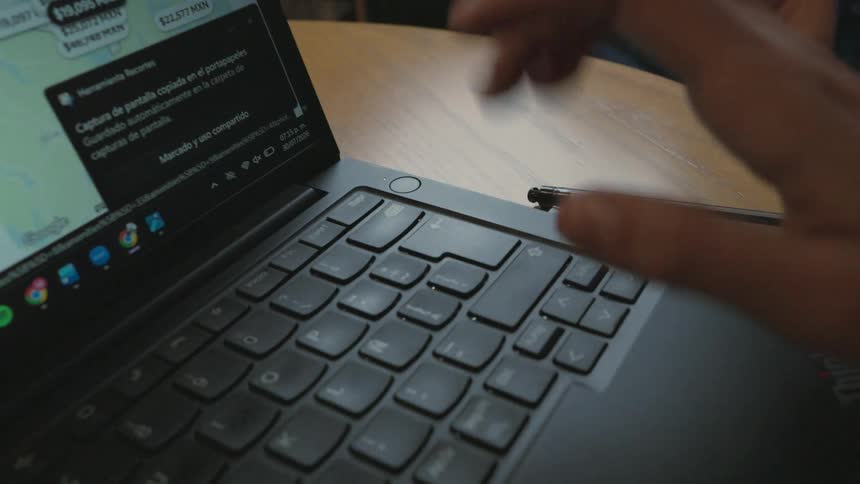 Close-up shot of a person's hands typing on a laptop keyboard while browsing a travel accommodation website