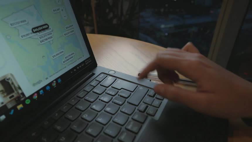 Close-up shot of a person's hands browsing a travel rental website on a laptop at night