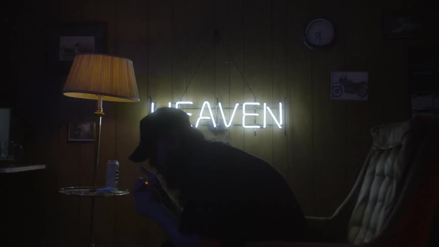 A man leans forward lighting a cigarette