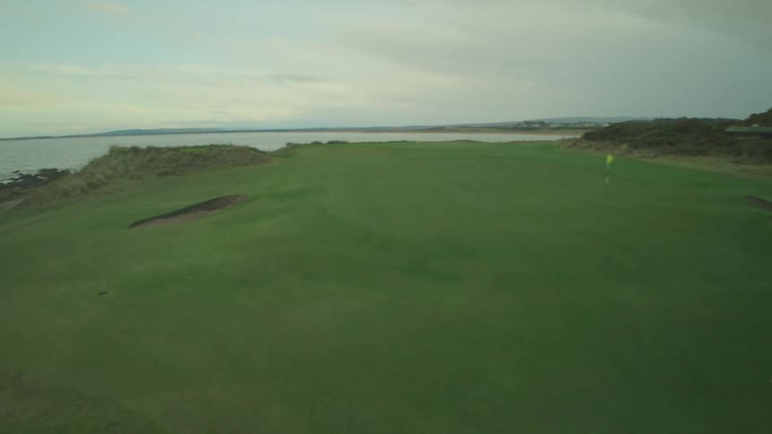 A lone sheep grazes on a lush green coastal golf course before an aerial camera pulls back to reveal the stunning seaside landscape