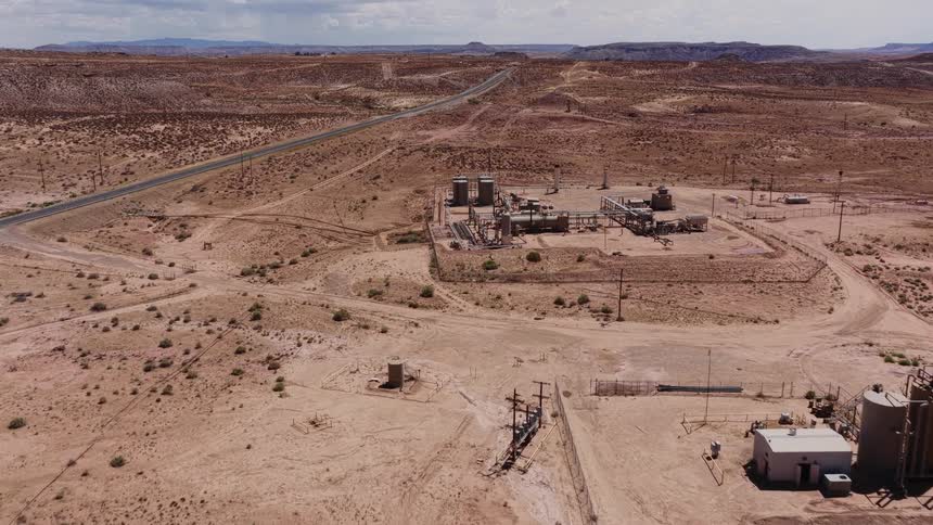 An aerial view of an oil and gas processing facility located in a vast, remote desert landscape