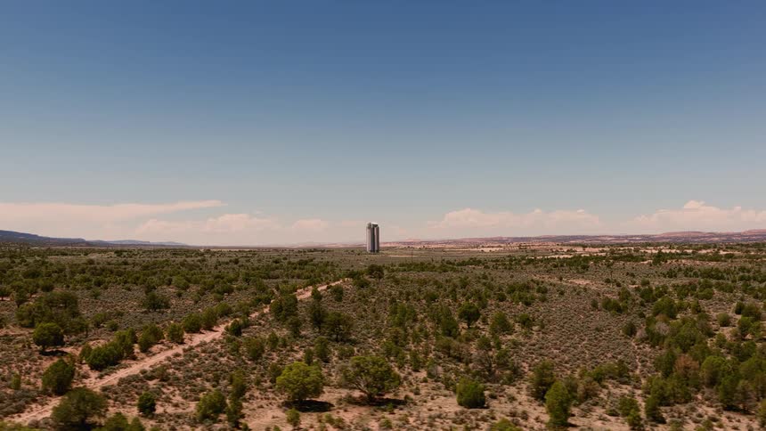 Slow aerial pullback reveals a tall, futuristic building isolated in a sprawling desert landscape