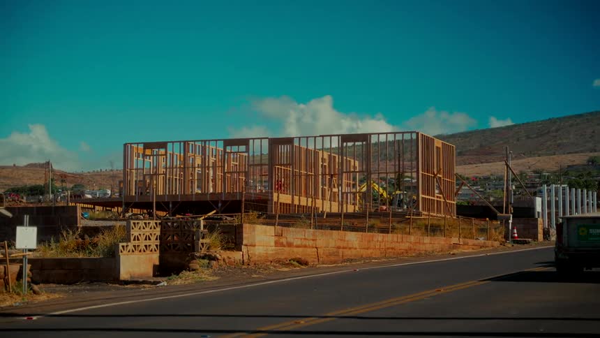 A time-lapse captures the framing of a new house being built on a sunny day with clouds passing overhead