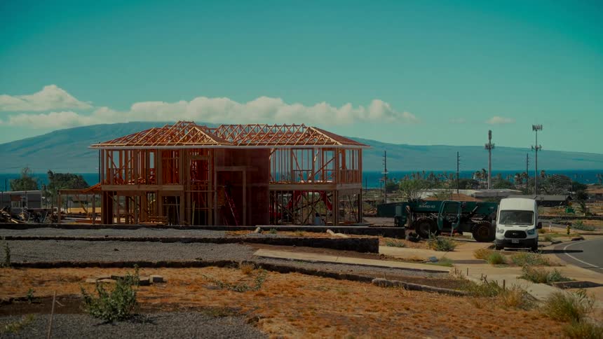 Time-lapse of a wooden house frame being constructed on a sunny day with a beautiful ocean and island view in the background