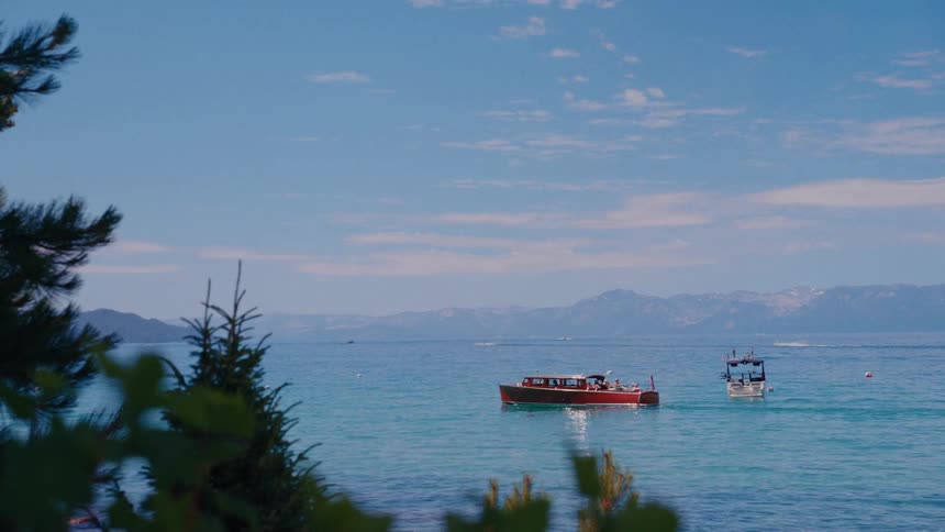A classic wooden boat floats on the tranquil turquoise waters of a mountain lake on a beautiful sunny day