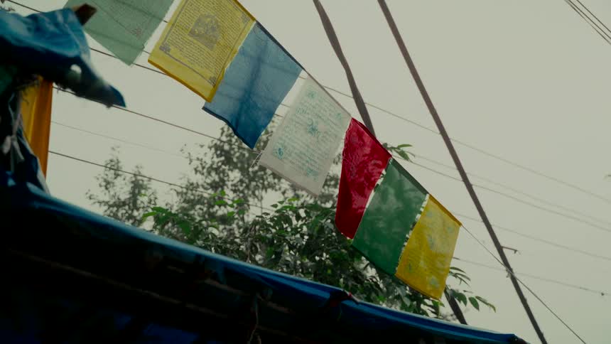 A string of Buddhist prayer flags waves in the wind under a grey, rainy sky