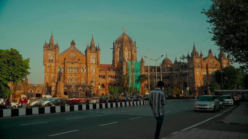 A man walks past the historic Chhatrapati Shivaji Maharaj Terminus building in Mumbai, India during a golden sunset