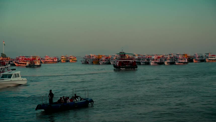 A slow-motion view of various boats and ferries in a busy harbor during a calm, beautiful sunset