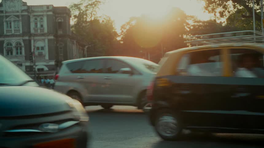 A slow-motion view of bustling city traffic navigating an intersection as the golden hour sun casts a warm glow