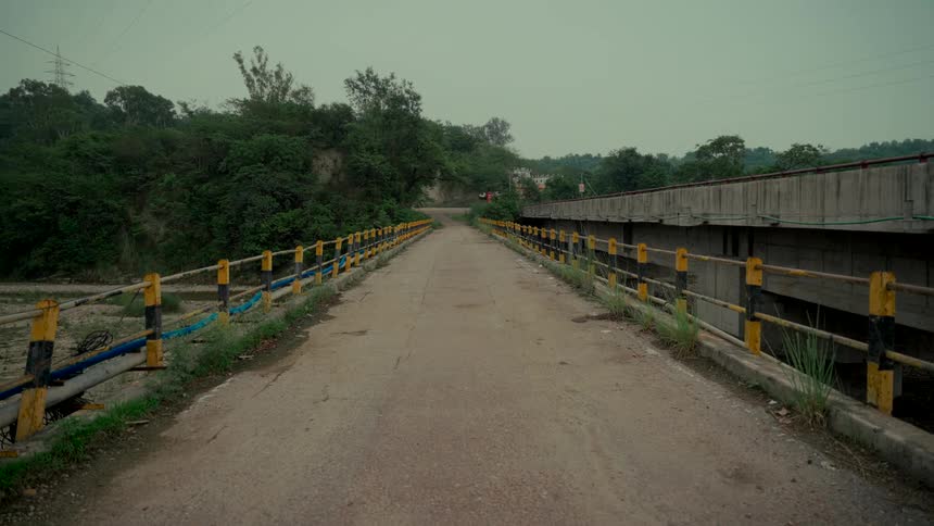 Static shot of an old, unused rural bridge alongside a modern concrete bridge on an overcast day