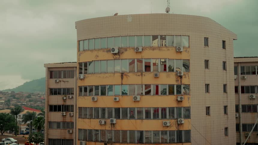 Static shot of a weathered, curved urban building in a sprawling city on a cloudy day