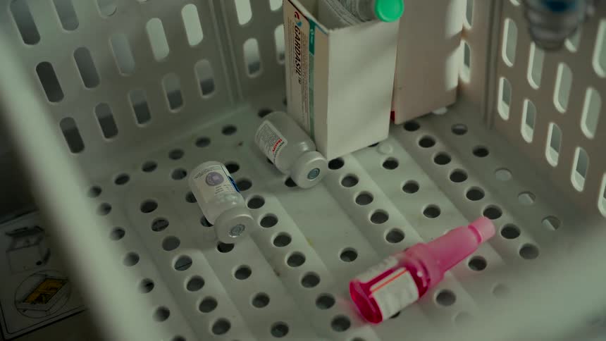 A close-up view of discarded vaccine vials and medical supplies in a white container