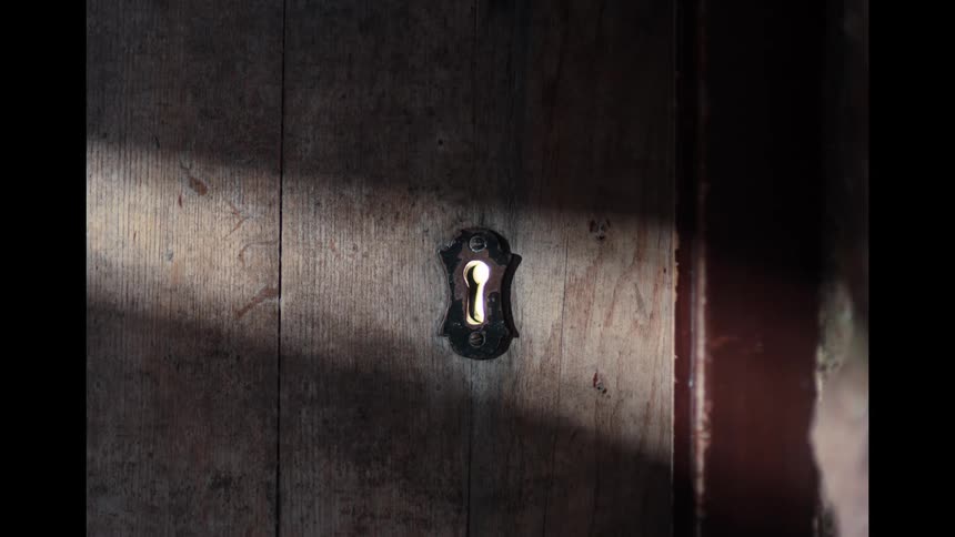 Light from a mysterious room shines through the keyhole of an old wooden door