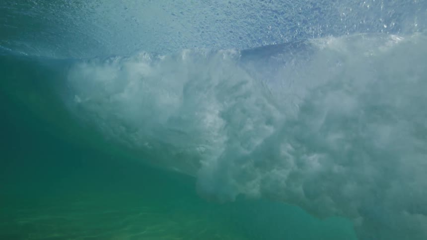 Slow motion underwater footage captures the beauty of a powerful ocean wave as it swells and breaks
