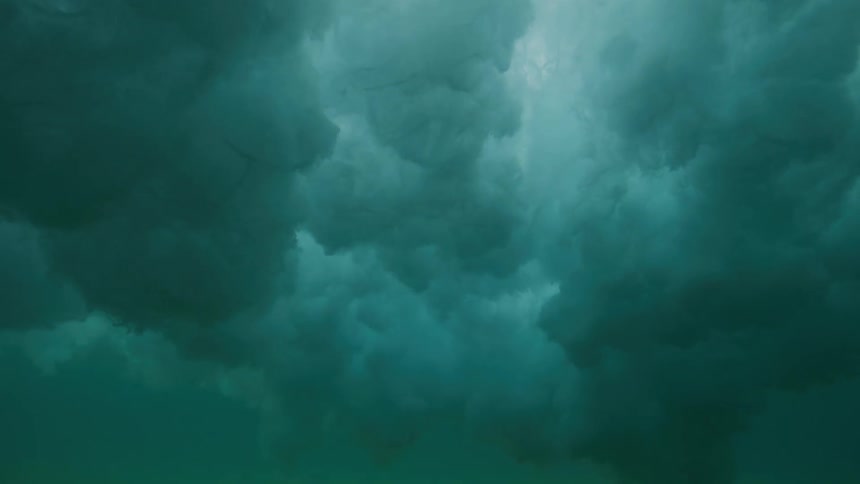 An underwater slow-motion view captures a massive wave as it crests overhead, transforming the calm sea into a turbulent, dark, and cloudy seascape