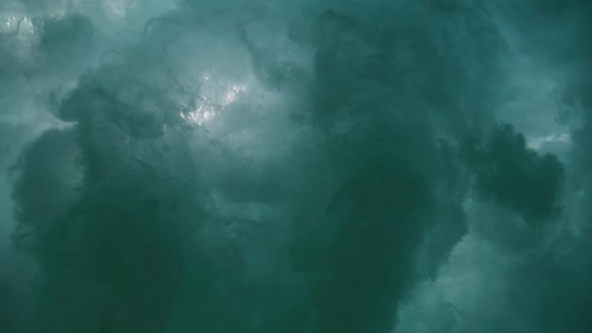 Slow motion underwater view of a powerful ocean wave curling and breaking from below