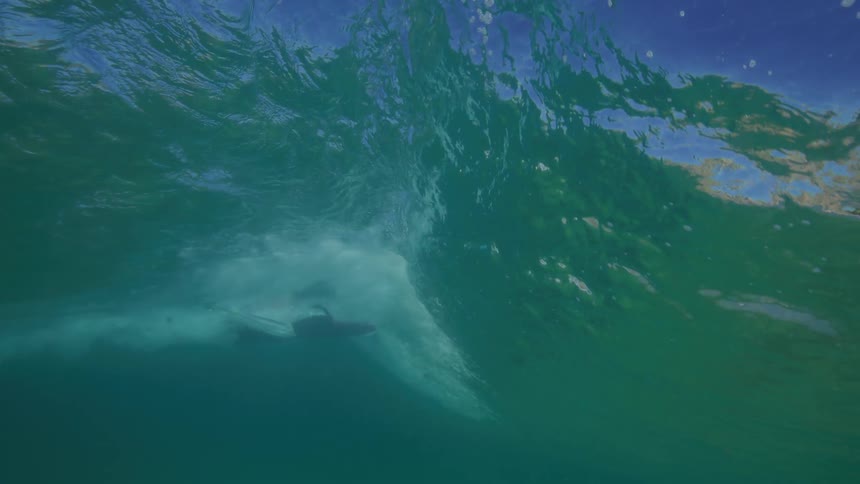 An incredible underwater slow-motion view shows a surfer gracefully riding inside a breaking ocean wave