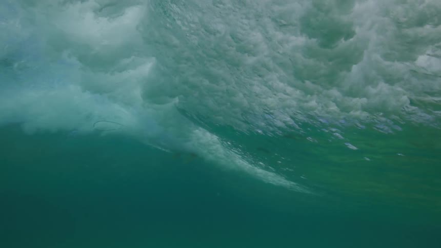 An incredible slow-motion underwater view of a surfer riding a large, powerful ocean wave
