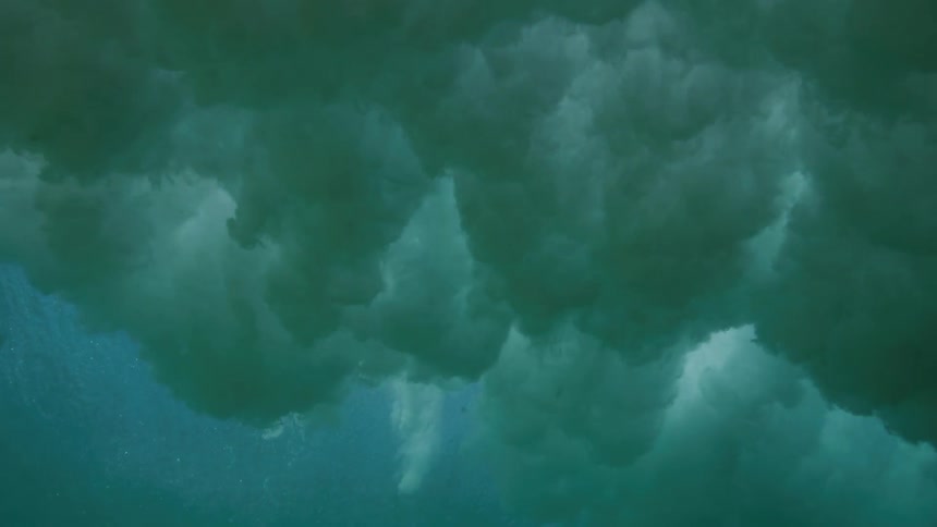 An immersive underwater perspective captures a powerful ocean wave breaking in slow motion