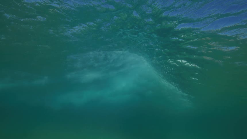 An underwater view of a large ocean wave breaking in slow motion