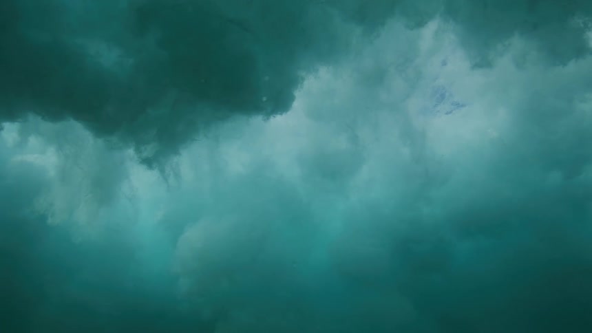 Slow motion underwater view of a powerful ocean wave breaking and creating a turbulent, cloudy surface