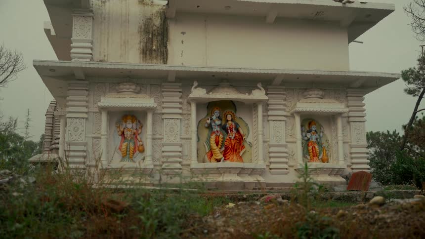A static shot captures the detailed, colorful statues of Hindu deities like Radha and Krishna set into the white marble walls of a temple