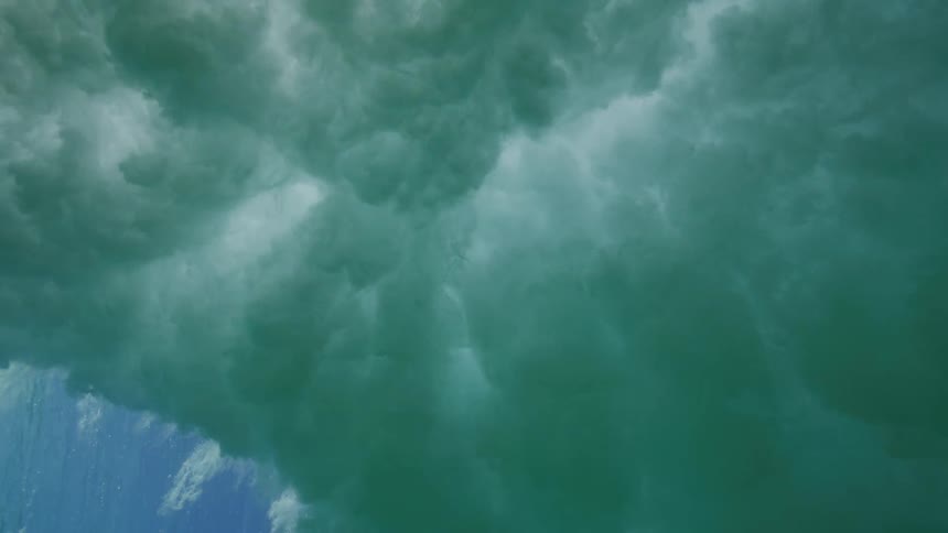 An incredible underwater perspective shows a powerful ocean wave breaking overhead in dramatic slow motion