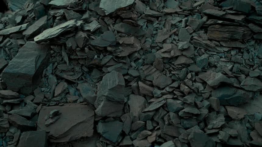 Static close-up shot of a pile of dark, shattered slate rocks