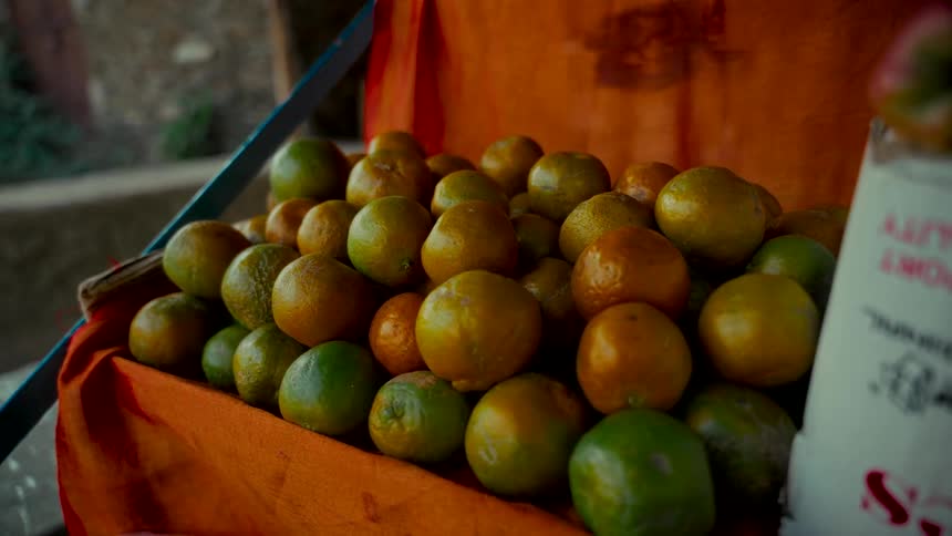 A close-up shot of fresh oranges displayed for sale on an orange cloth at an outdoor market stall