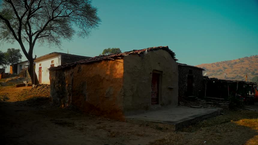 A rustic mud house in a quiet Indian village basks in the warm glow of the morning sun